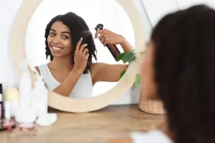 Young attractive black female using hair straightener products