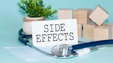 SIDE EFFECTS - words written on white medical card, with medicine mask, stethoscope, green flower and wooden bloc