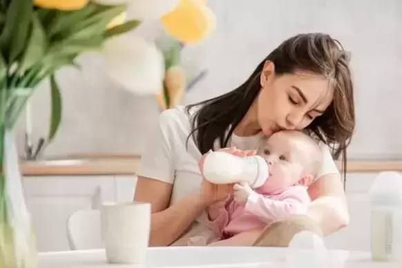 Mother feeding baby with bottle sitting up