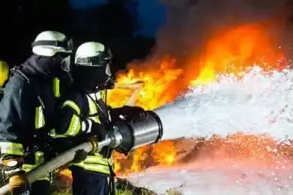 Two firefighters using firefighting foam to put out fire