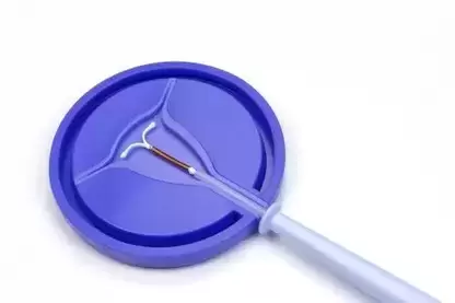 A Paragard IUD lying in a blue circular holding dish on a solid white background