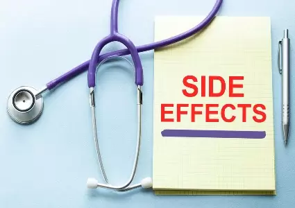 Side effects written in red ink on a yellow notepad next to medical equipment.
