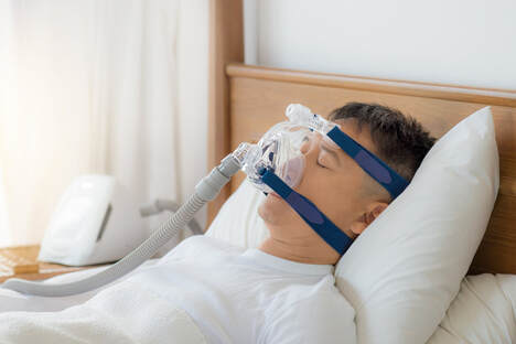 Man sleeping with a Philips CPAP mask on with blue straps