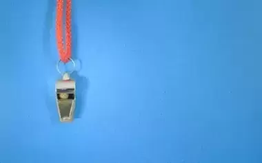 whistle with red string hanging in front of blue background